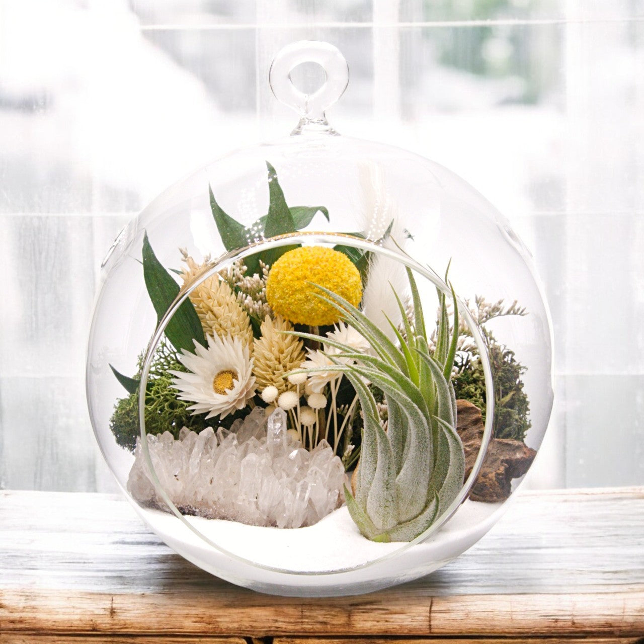 Glass bubble airplant terrarium with sand, dried flower bouquet, crystal quartz cluster