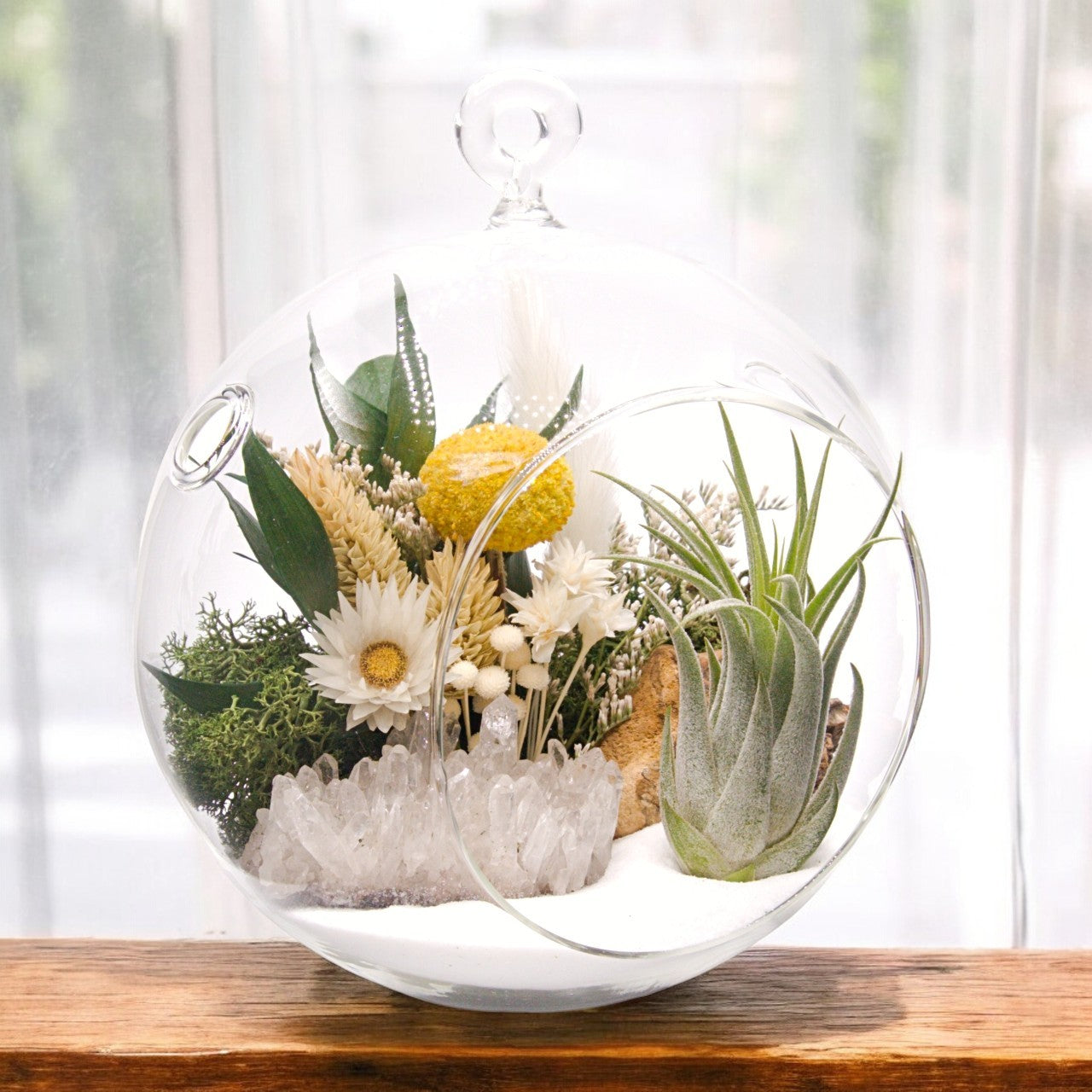 Glass bubble airplant terrarium with sand, dried flower bouquet, crystal quartz cluster