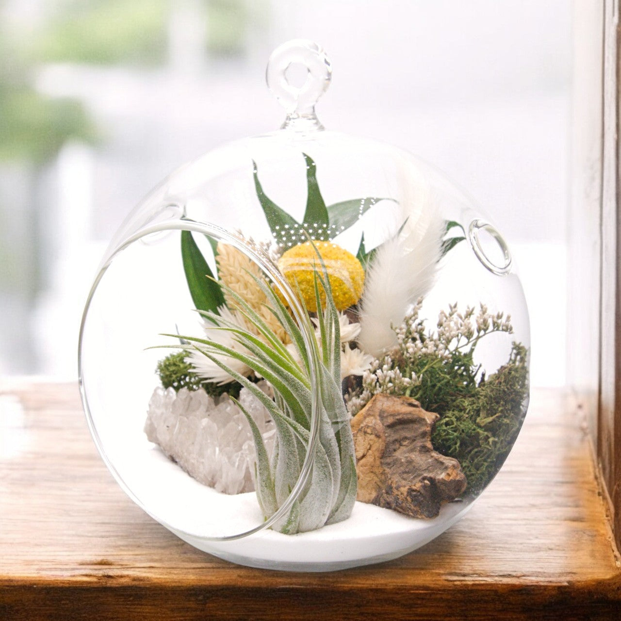 Glass bubble airplant terrarium with sand, dried flower bouquet, crystal quartz cluster