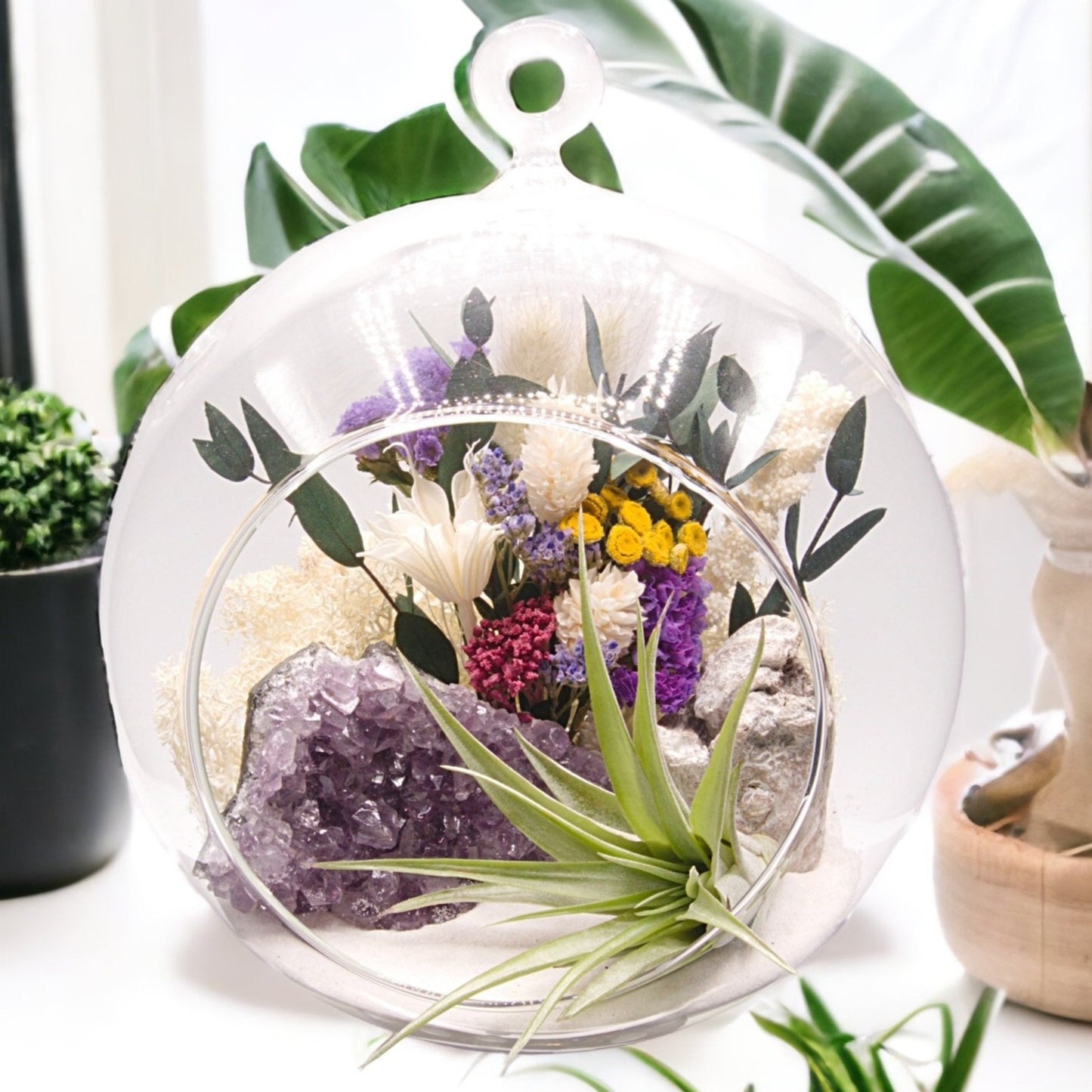 Airplant terrarium in a glass bubble vase with an amethyst crystal and dried flowers