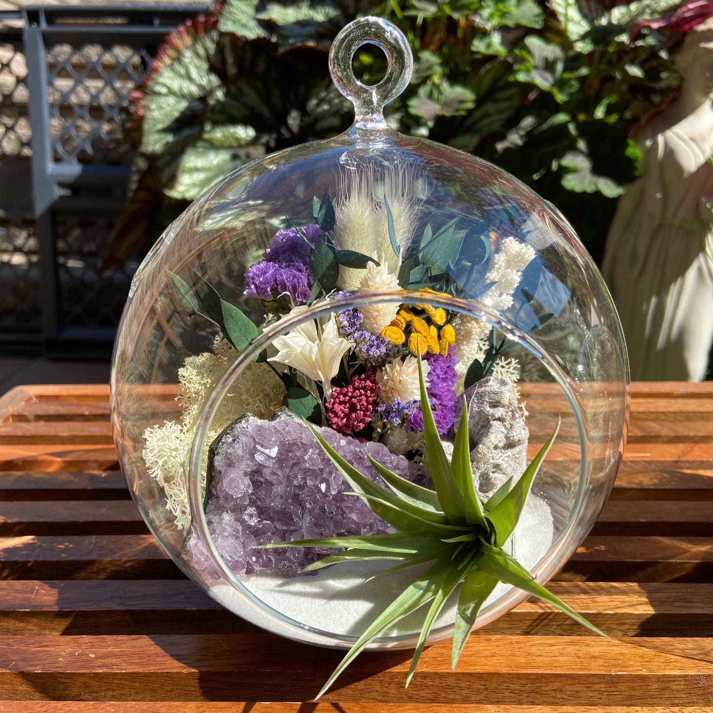 Airplant terrarium in a glass bubble vase with an amethyst crystal and dried flowers