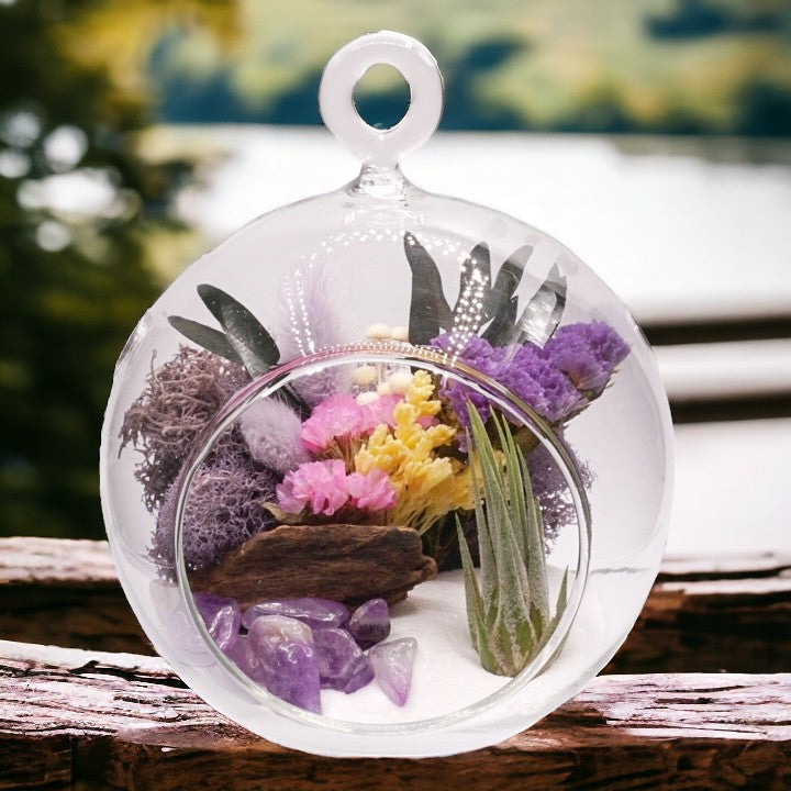 Glass bubble airplant terrarium with purple dried flowers, sand, moss, wood, amethyst crystals and an airplant