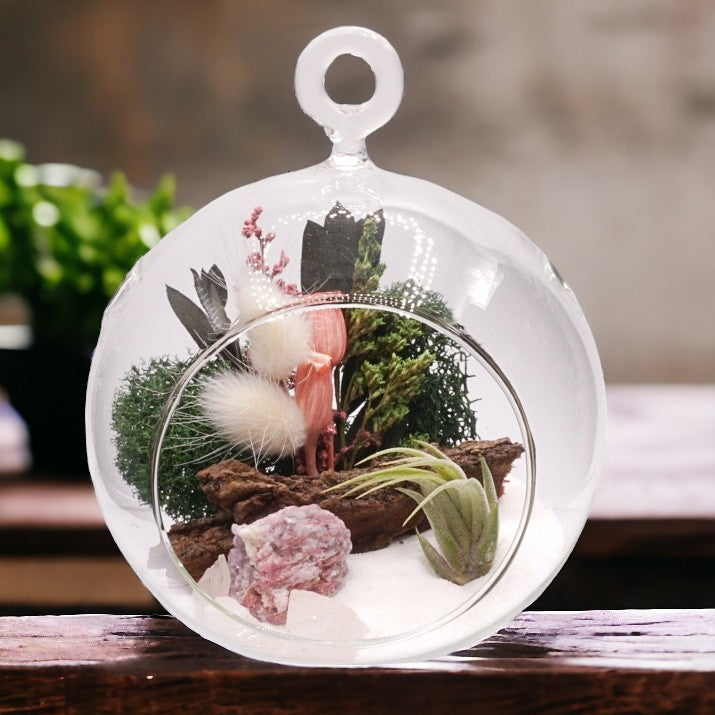 Glass bubble airplant terrarium with pink dried flowers, sand, moss, wood, rose quartz or pink tourmaline crystals and an airplant