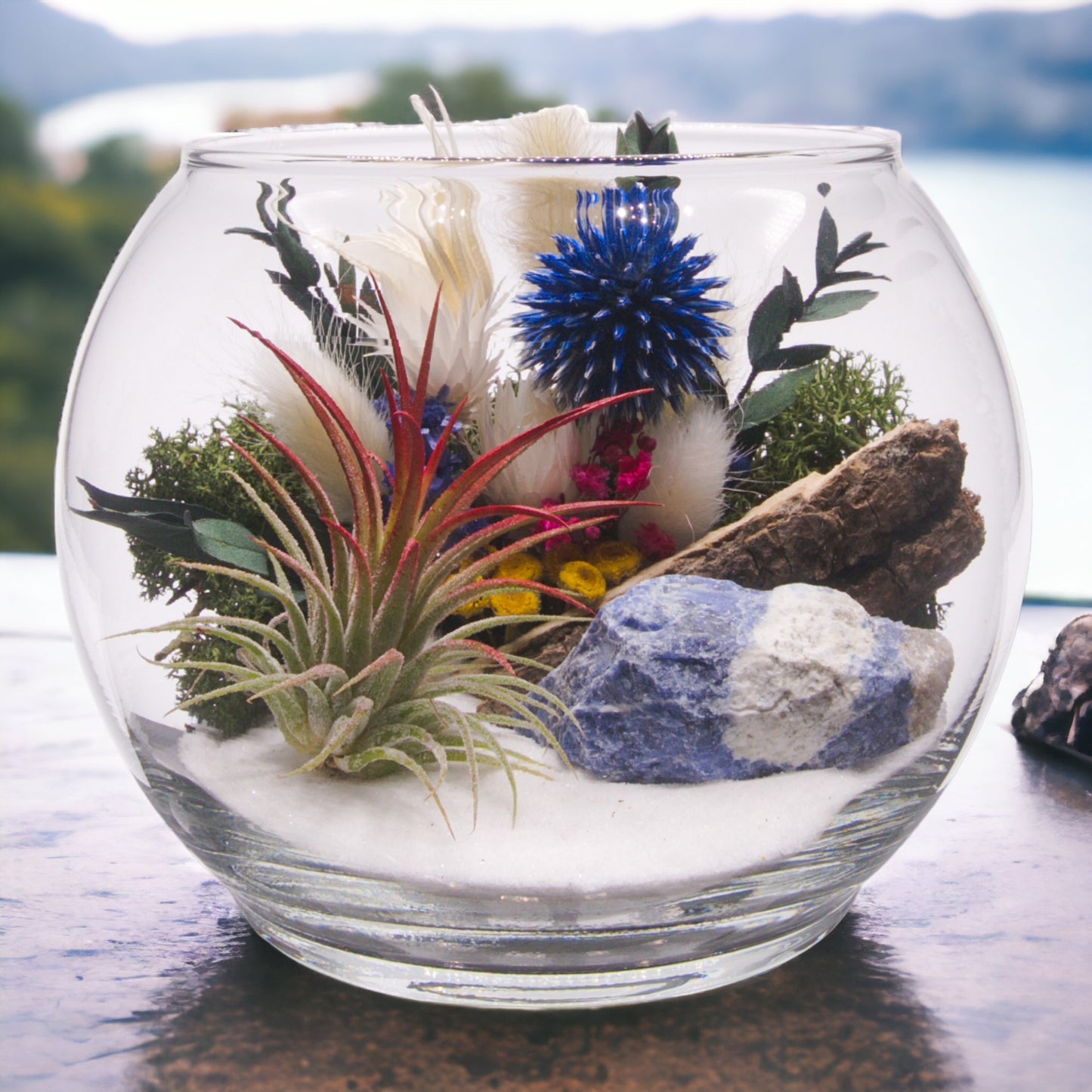 Glass bowl terrarium with dried flowers, an airplant, sand, sodalite stone