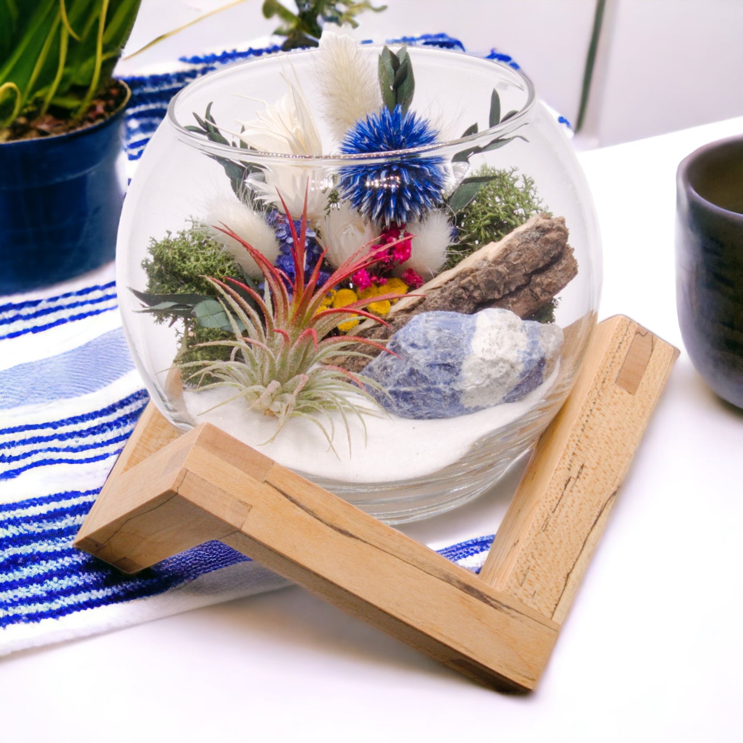 Glass bowl terrarium with dried flowers, an airplant, sand, sodalite stone