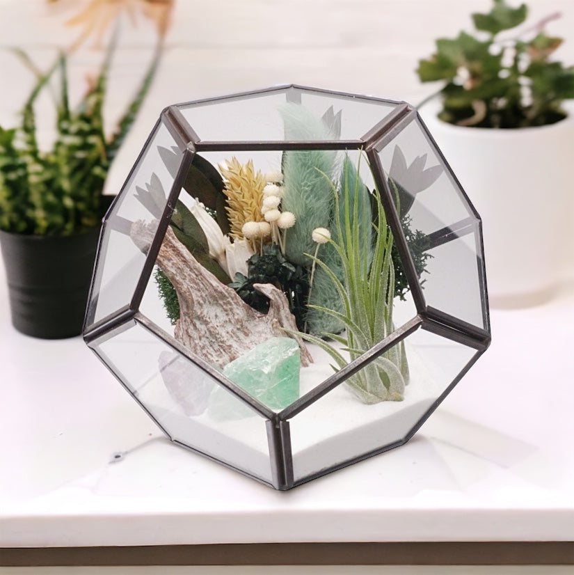 Black-rimmed geometric glass terrarium with an airplant, dried flower bouquet with turquoise accents, sand, moss and green fluorite e crystals
