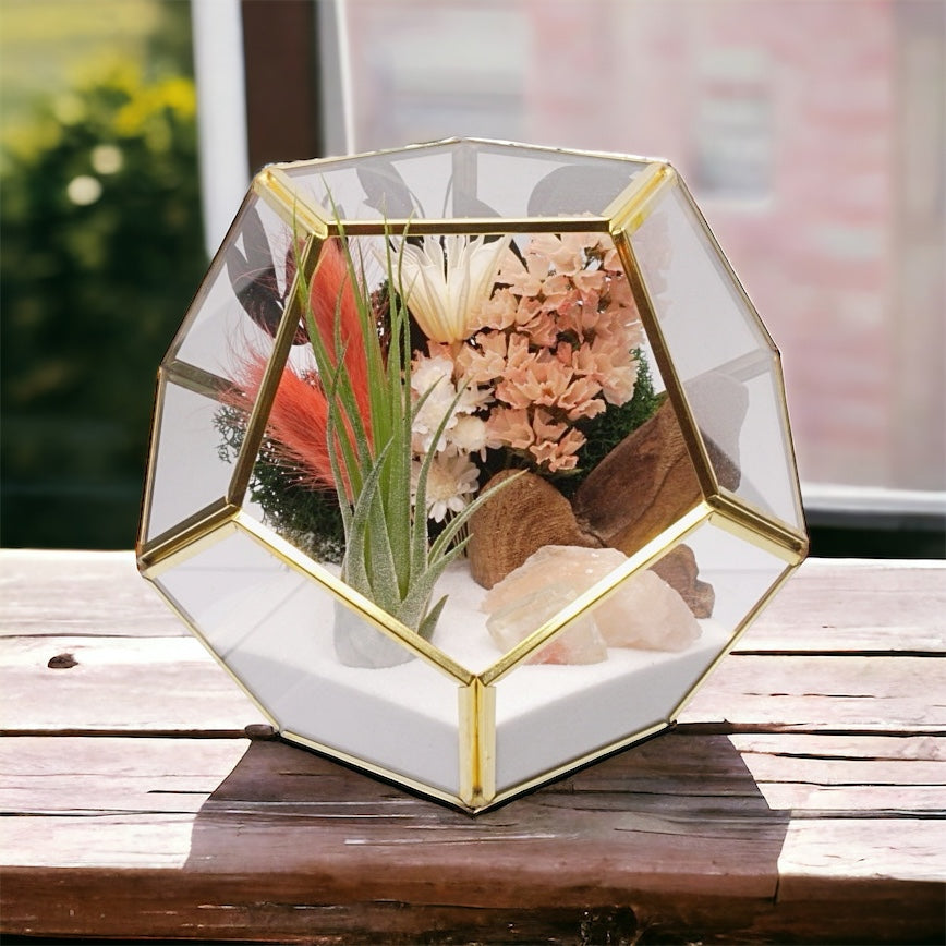 Gold-rimmed glass geometric airplant terrarium with peach coloured dried flowers, moss, sand and stilbite crystals