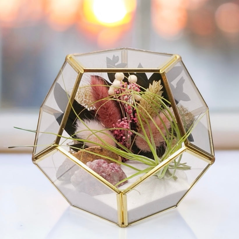 Airplant terrarium in a gold rimmed geometric glass vase with pink bouquet of dried flowers, moss, wood and pink tourmaline crystals