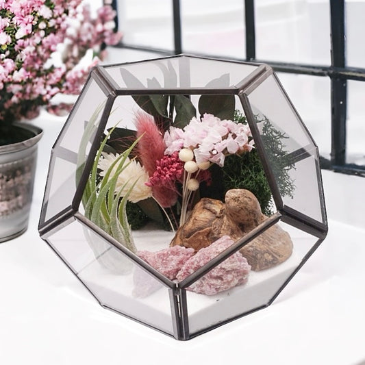 Airplant terrarium in a black rimmed geometric glass vase with pink bouquet of dried flowers, moss, wood and pink tourmaline crystals