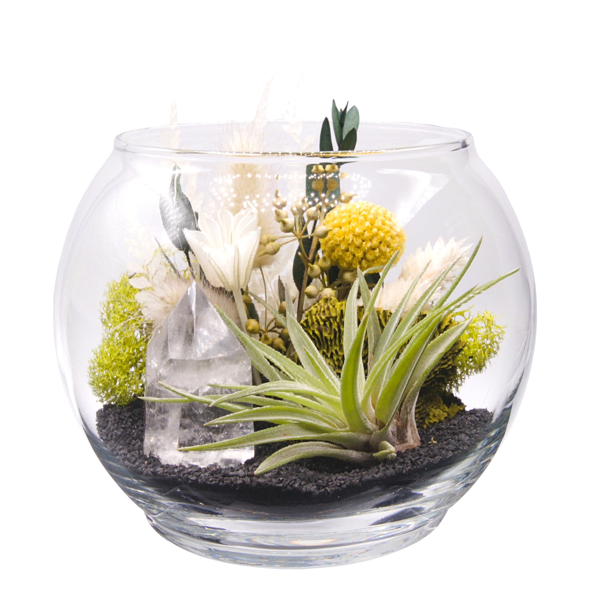 A glass bowl airplant terrarium with black sand, a bouquet of dried flowers, green moss, a dried mushroom and a crystal quartz tower.