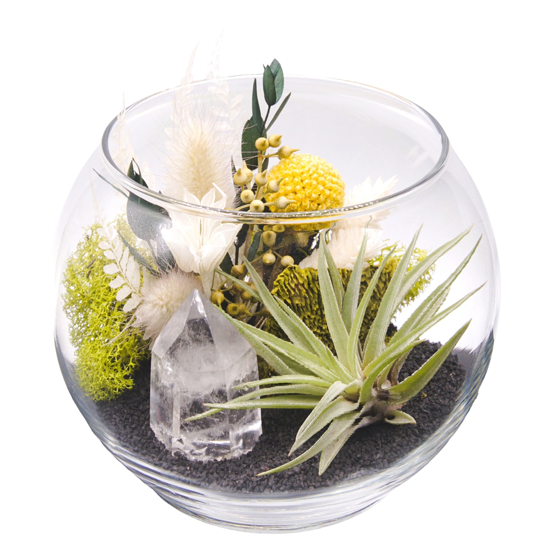 A glass bowl airplant terrarium with black sand, a bouquet of dried flowers, green moss, a dried mushroom and a crystal quartz tower.
