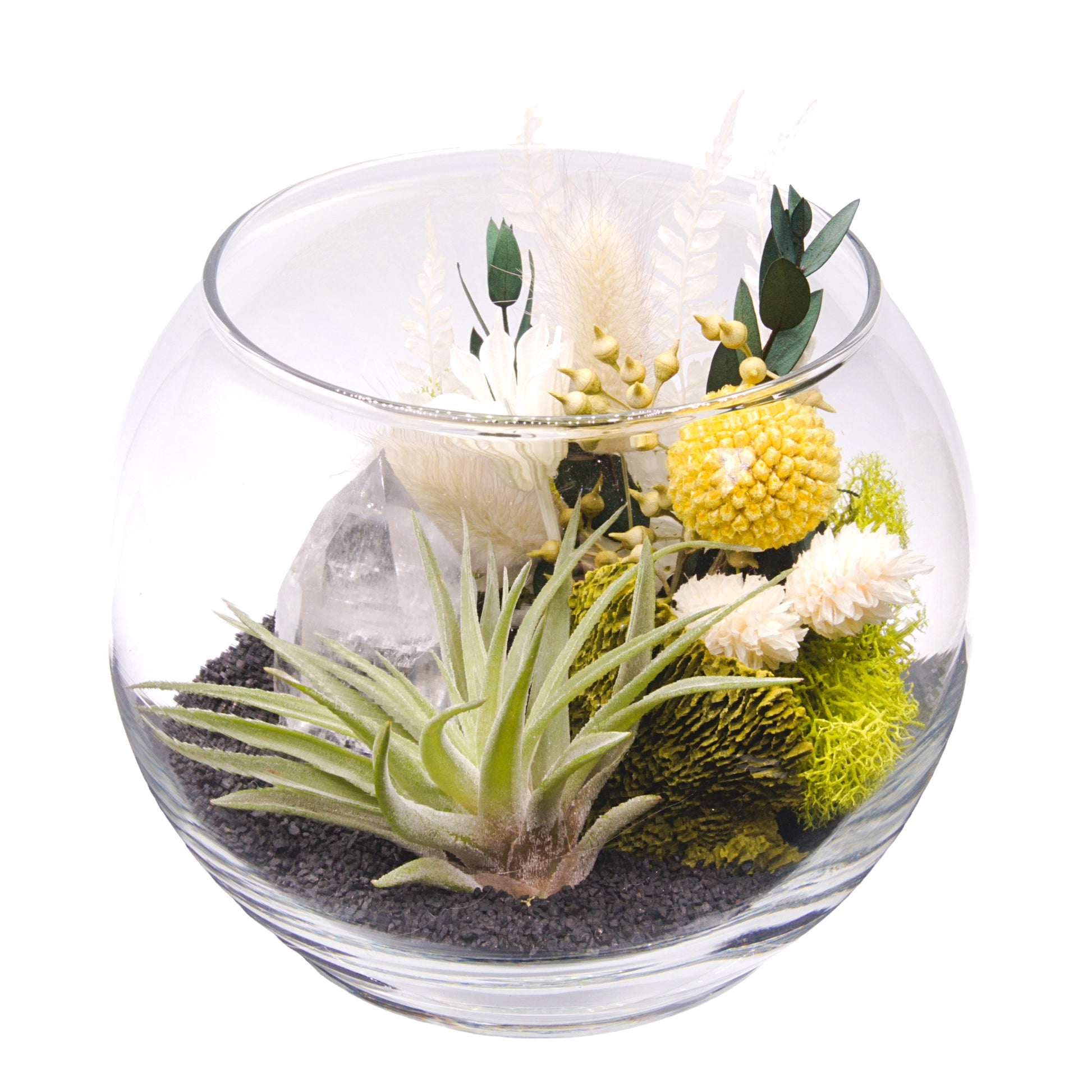 A glass bowl airplant terrarium with black sand, a bouquet of dried flowers, green moss, a dried mushroom and a crystal quartz tower.