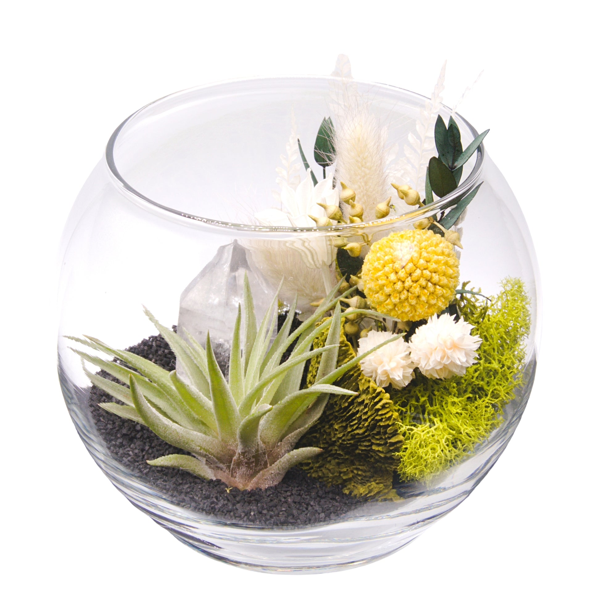 A glass bowl airplant terrarium with black sand, a bouquet of dried flowers, green moss, a dried mushroom and a crystal quartz tower.